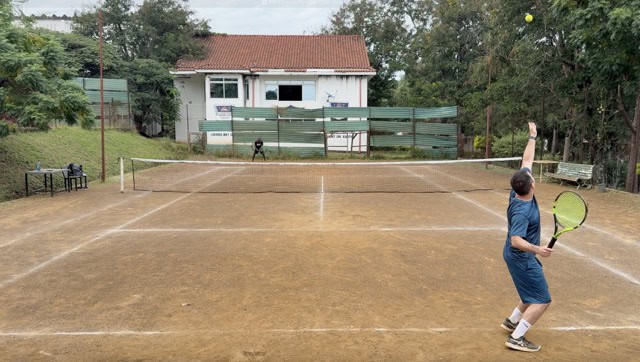 American tourist plays tennis with Kenyan player (Samsan) at Nyanza club in Kisumu, Kenya.